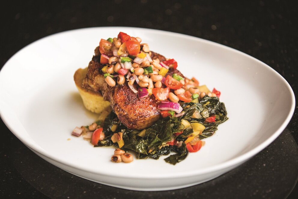 Sauteed chicken garnished with black eye peas over greens