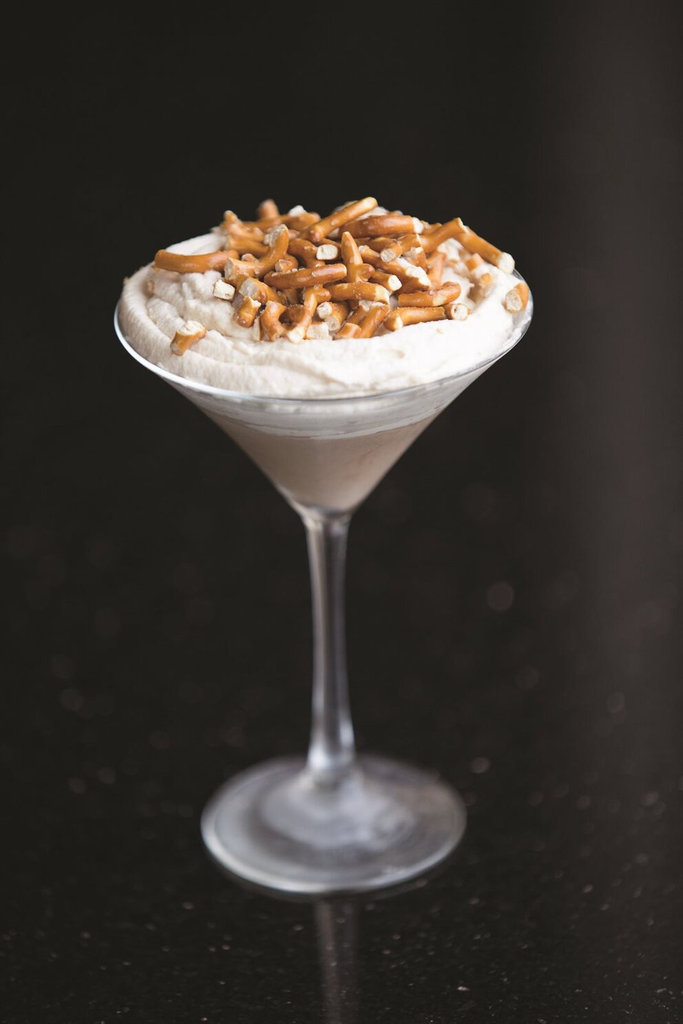Chocolate mouse with whipped cream and pretzel pieces in a martini glass